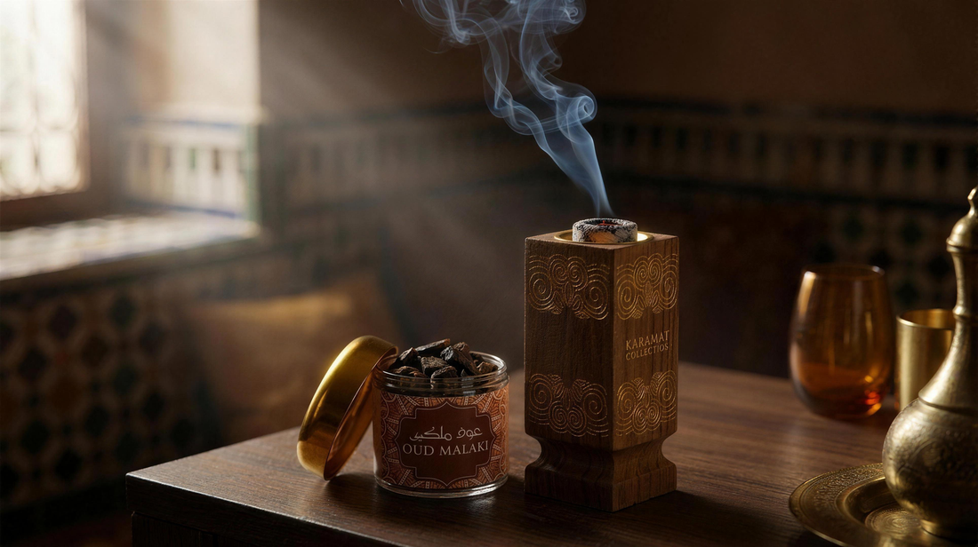 Brûleur à bakhour en bois sculpté Karamat, charbon incandescent recouvert de cendre et filet de fumée d'encens, à côté d'une boîte de bakhour Mabsous Oud Malaki 30 g ouverte.