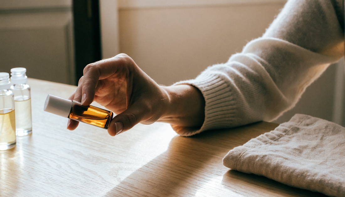 Flacon de parfum sans alcool de 8 ml tenu dans la main, sur une table en bois clair en lumière naturelle