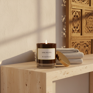 Bougie parfumée 1001 Nuits Karamat allumée sur une console en travertin