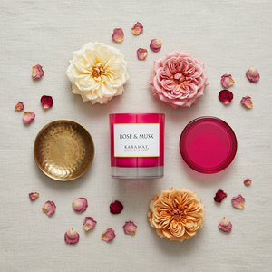Bougie parfumée Rose & Musk Karamat à plat avec roses fraîches
