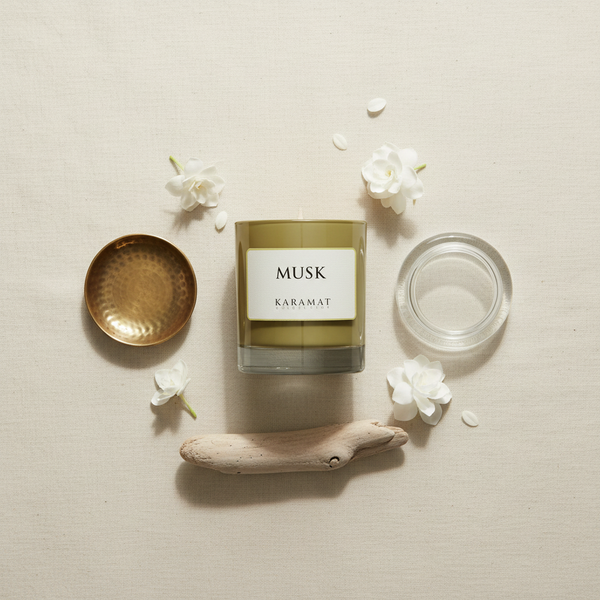 Bougie parfumée Musk Karamat à plat avec fleurs blanches et bois flotté