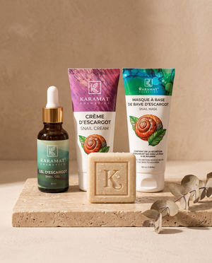 Rituel Bave d'Escargot Karamat : savon 125 g, gel 33 ml, crème 50 ml et masque 100 ml alignés sur travertin