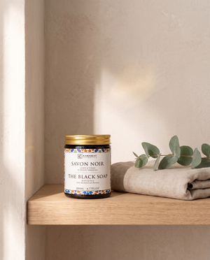 Pot de savon noir beldi 200 ml sur une étagère de salle de bain avec linge et eucalyptus
