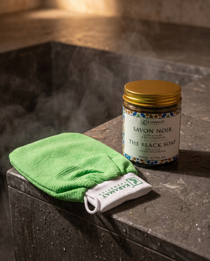 Savon noir beldi 200 ml Karamat Collection et gant kessa vert sur une pierre de hammam humide